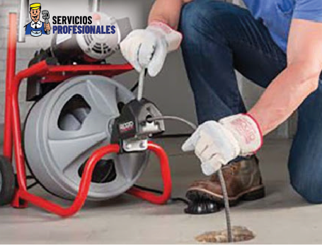 Técnico utilizando máquina eléctrica para destape de desagüe.